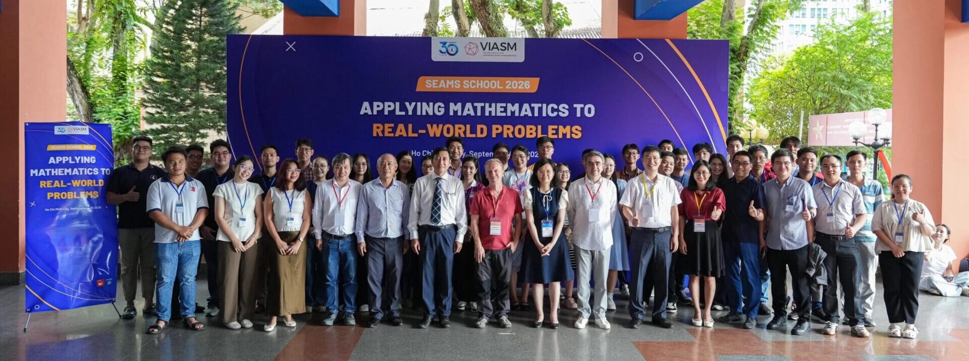 Group photo of SEAMS School 2026 participants and lecturers in front of the school's banner