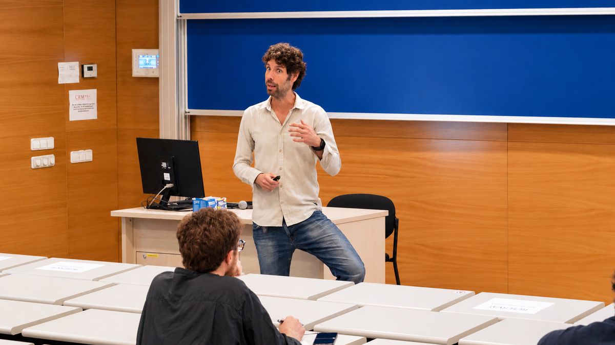 Diego Vidaurre leans against the desk at the front of the lecture hall as he speaks.