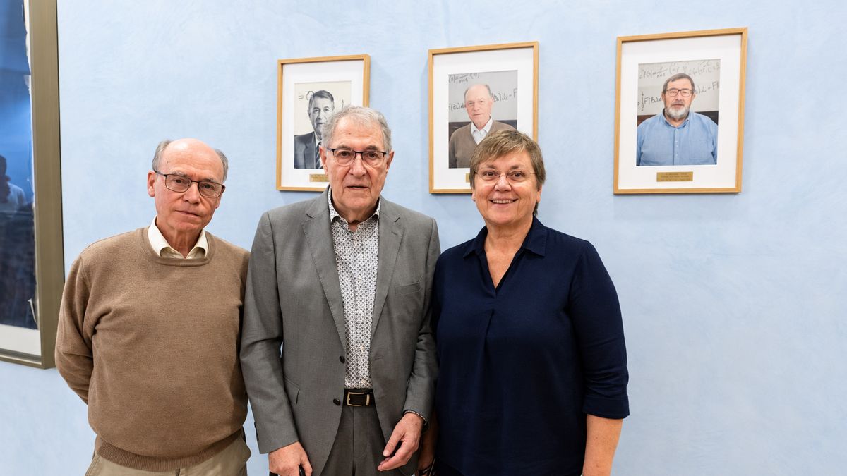 Three people stand in front of the three framed portraits of the CRM’s former directors.